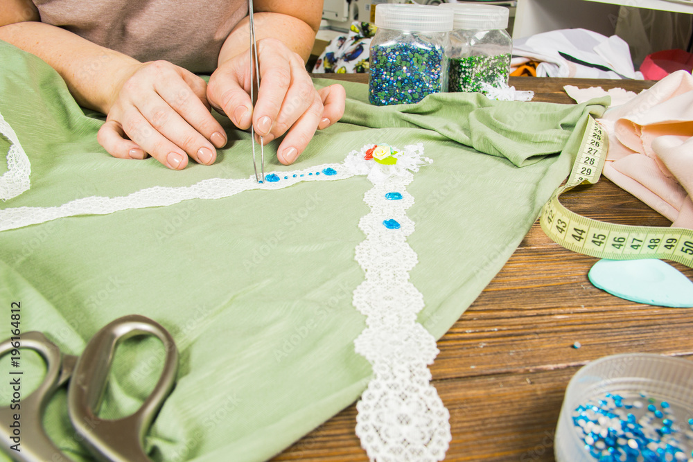 A woman is making jewelry, a home workshop. Female hands that create an accessory with beads and ribbons. Beauty, creativity, the concept of handicraft. A woman is making jewelry, a home workshop. Female hands that create an accessory with beads and ribbons. Beauty, creativity, the concept of handicraft.