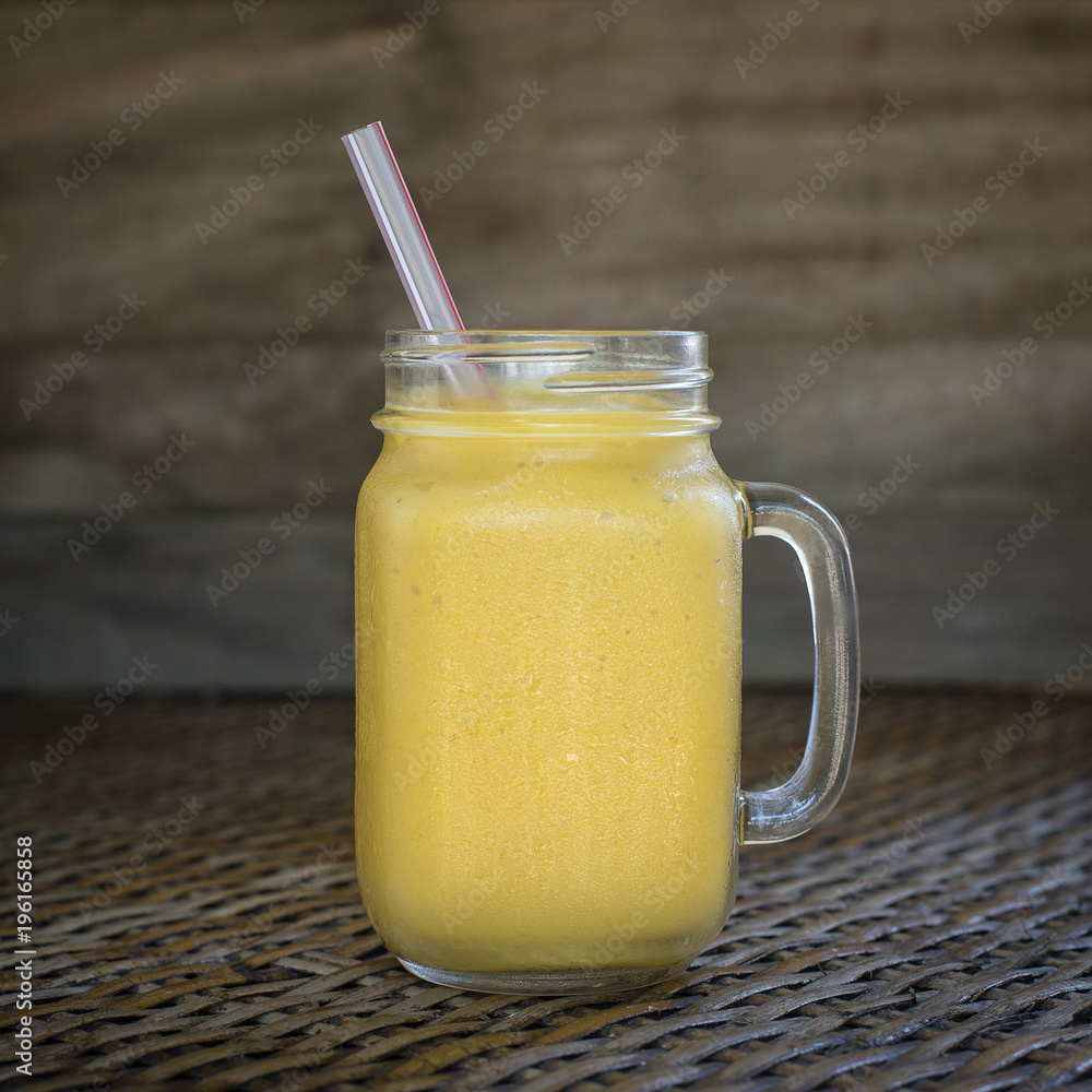 Fresh organic mango shake in glass mug on wooden table, close up Fresh organic mango shake in glass mug on wooden table, close up