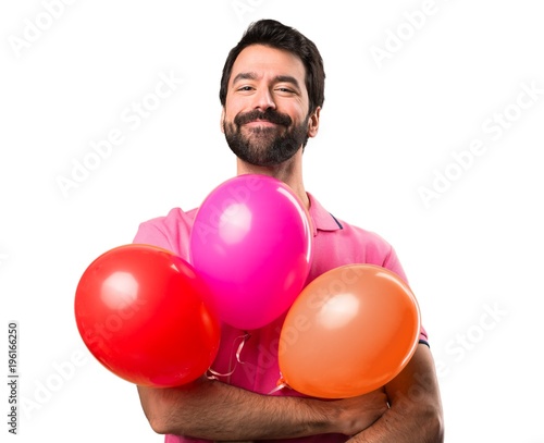Handsome young man holding balloons over isolated white background © luismolinero