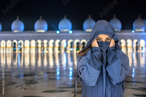Bild auf Leinwand Muslim woman wearing traditional Arab clothing  near Mosque during night