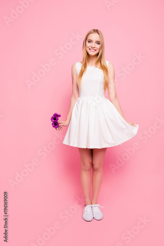 Vertical full-size full-length portrait of charming sweet cute tender gentle lovely innocent beautiful shy teenager touching skirt's bottom holding three flowers hand gumshoes shoe isolated background