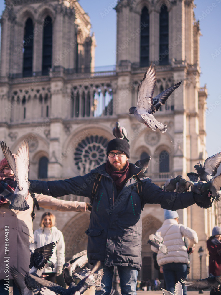 Man feeding pigeons in the square in front of the cathedral of Notre Dame