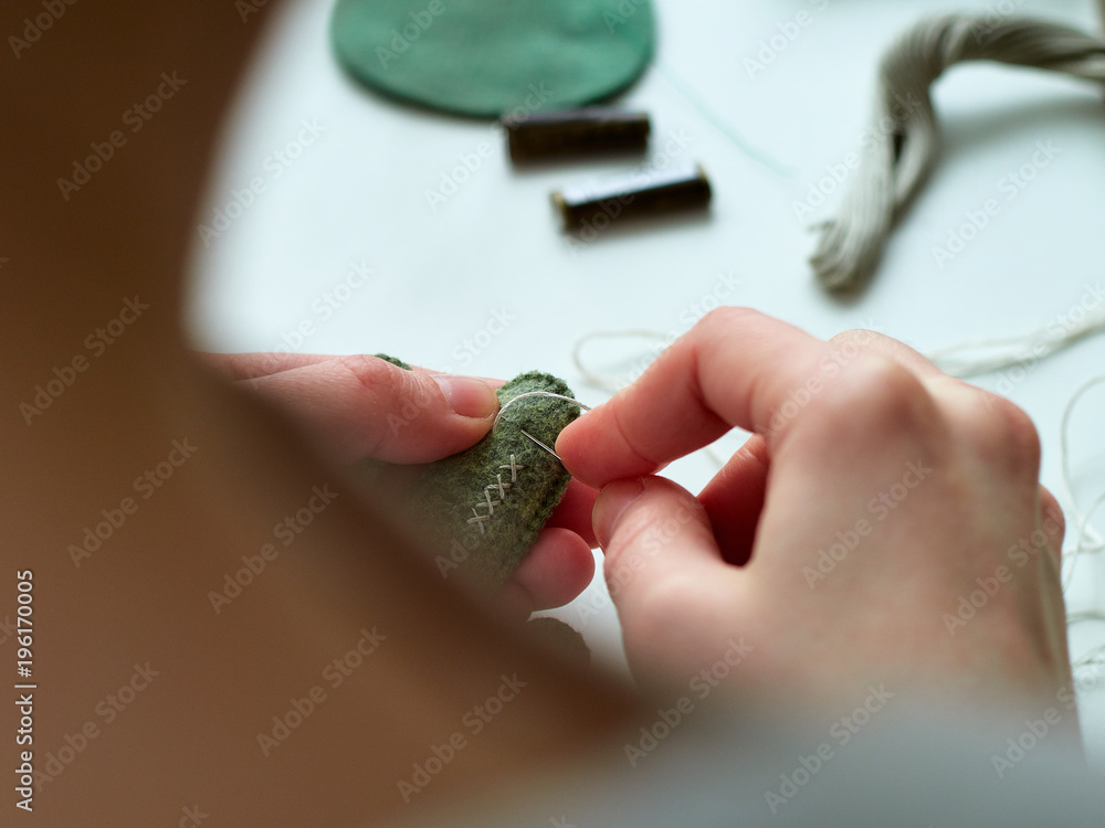 Fototapeta premium Step-by-step process of manual manufacturing baby crib mobile. Sewing a seam on a toy.