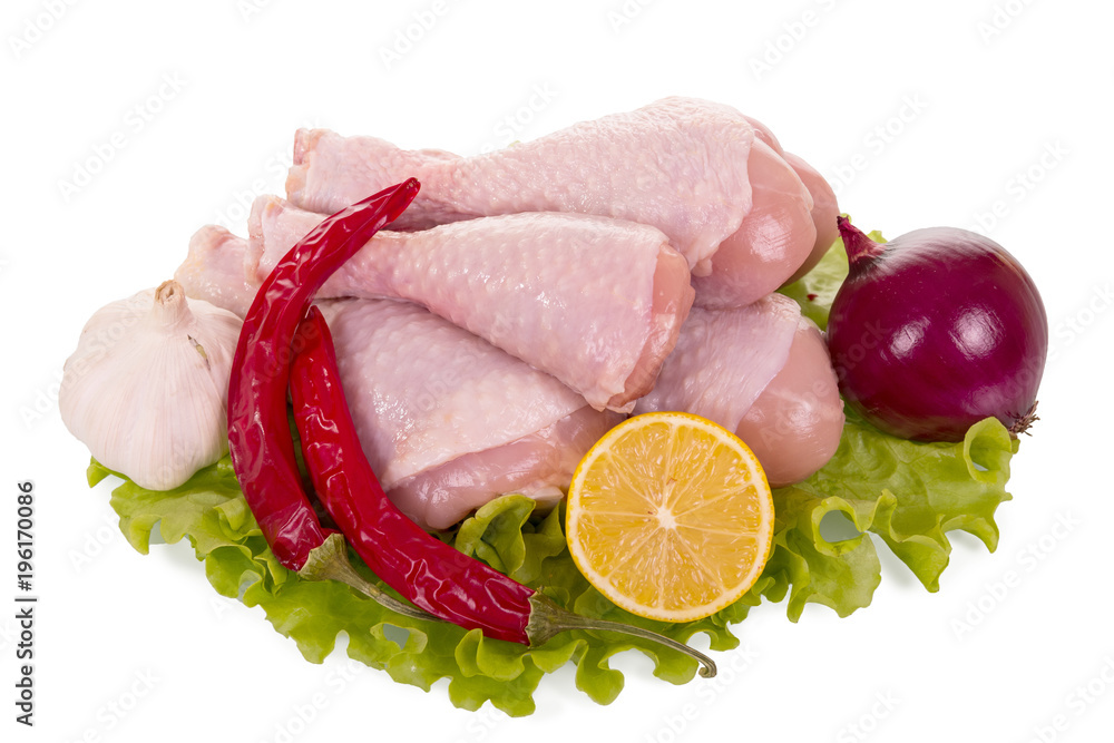 Chicken leg quarters on lettuce next to the onions, garlic, hot pepper isolated on white