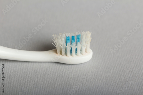 Old used toothbrush on grey. Close-up