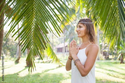 A beautiful young woman stands in a palm grove in the rays of the morning sun. Phangan, Thailand
