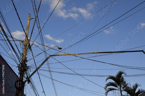 Postes e fios tampando um céu azul