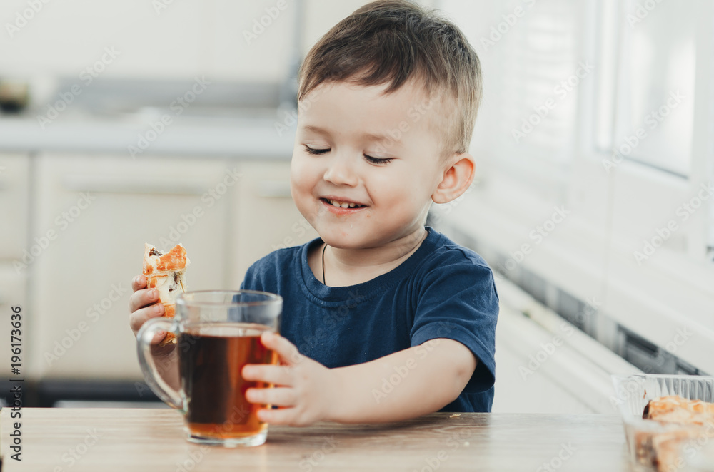 Beautiful baby sitting in the kitchen eating a delicious tube of condensed milk Beautiful baby sitting in the kitchen eating a delicious tube of condensed milk