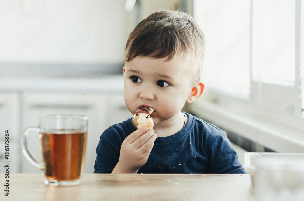 Beautiful baby sitting in the kitchen eating a delicious tube of condensed milk Beautiful baby sitting in the kitchen eating a delicious tube of condensed milk