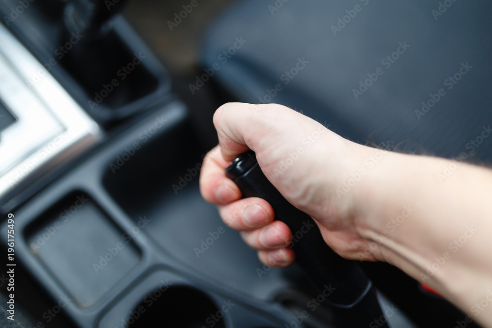 The driver pulls the hand brake lever. Male hand pulling the Parking brake using the hand brake