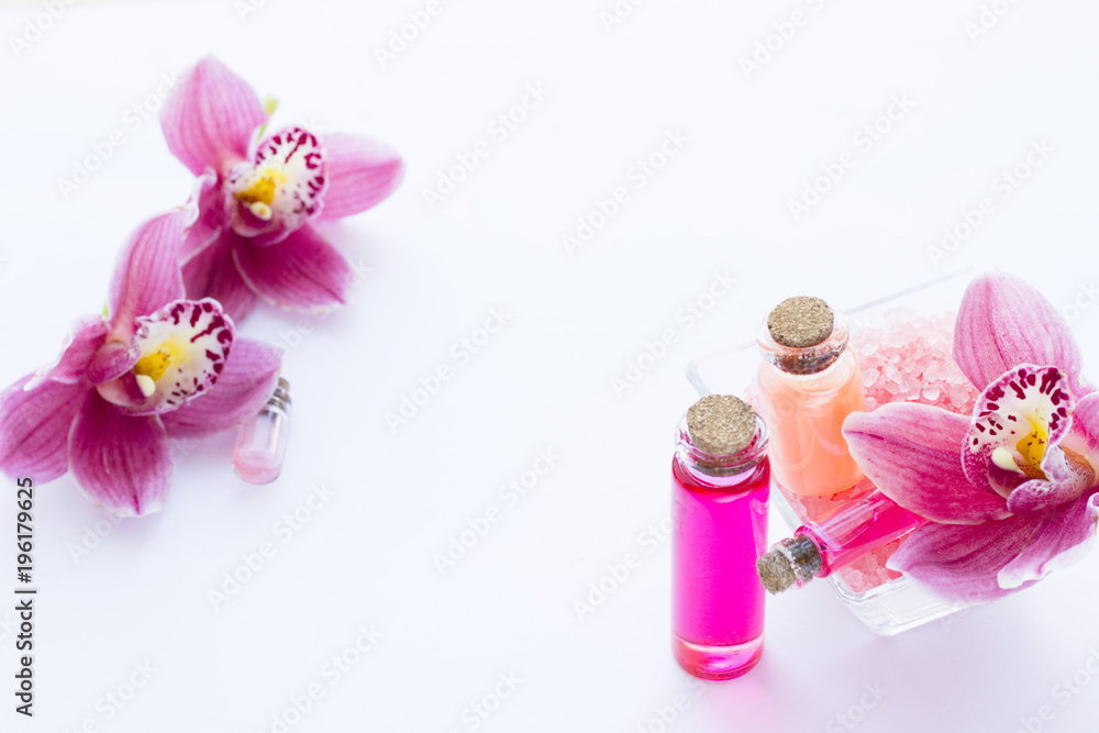 Spa and wellness setting with orchid and red oil in a bottle on wooden white background closeup