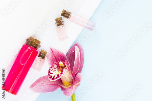 Spa and wellness setting with orchid and bottles with oil on blue background copyspace