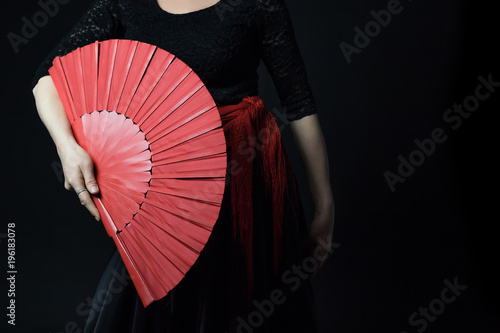 Fototapeta Low Key photo of Flamenco Dancer middle age woman posing with her red fan