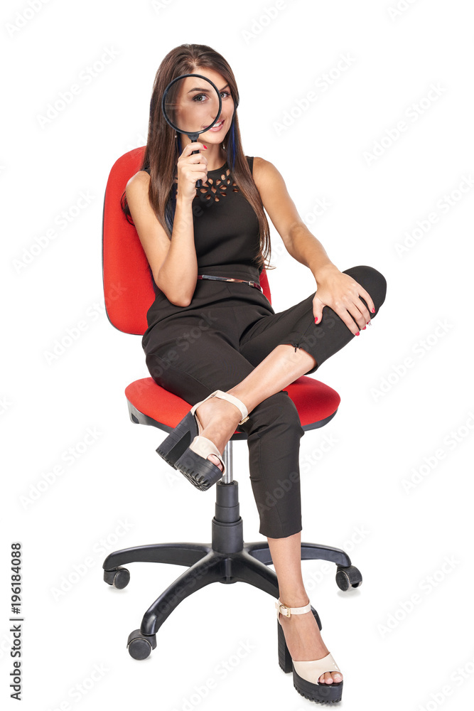 Fototapeta premium Smiling woman sitting on office chair looking at camera through magnifying glass, full length portrait