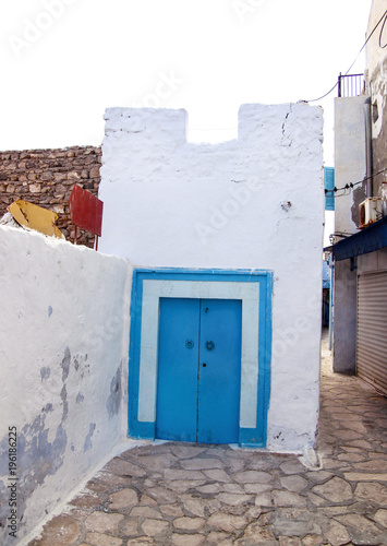 View of medina of tunisia old wall and wooden doors painted in blue and white on Mediterranean coast / Architecture Arabic style, travel, holiday. Tourist season, vacation / Oriental and traditional.