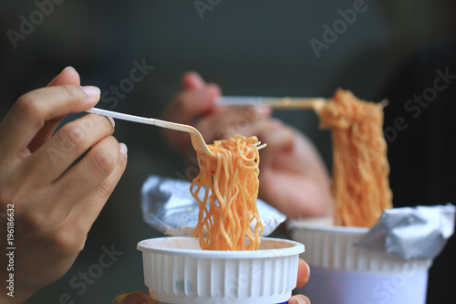 young woman hand holding plastic fork of instant noodles, Sodium diet high risk kidney failure.