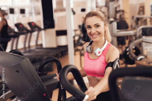 Woman with headphones running on treadmill at the gym. They look happy, fashionable and fit.