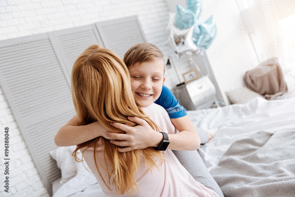 Fototapeta premium I love you. Happy cute delighted boy closing his eyes and smiling while hugging his mother