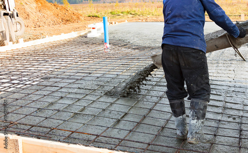 Closeup shot of concrete casting on reinforcing metal bars of floor in industrial construction site photo