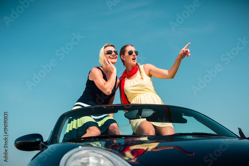 Woman having summer trip in convertible car stretching hands in the air with fun © Kzenon