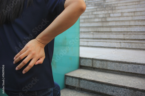 young woman with lower back pain while walking up the stairs, health concept