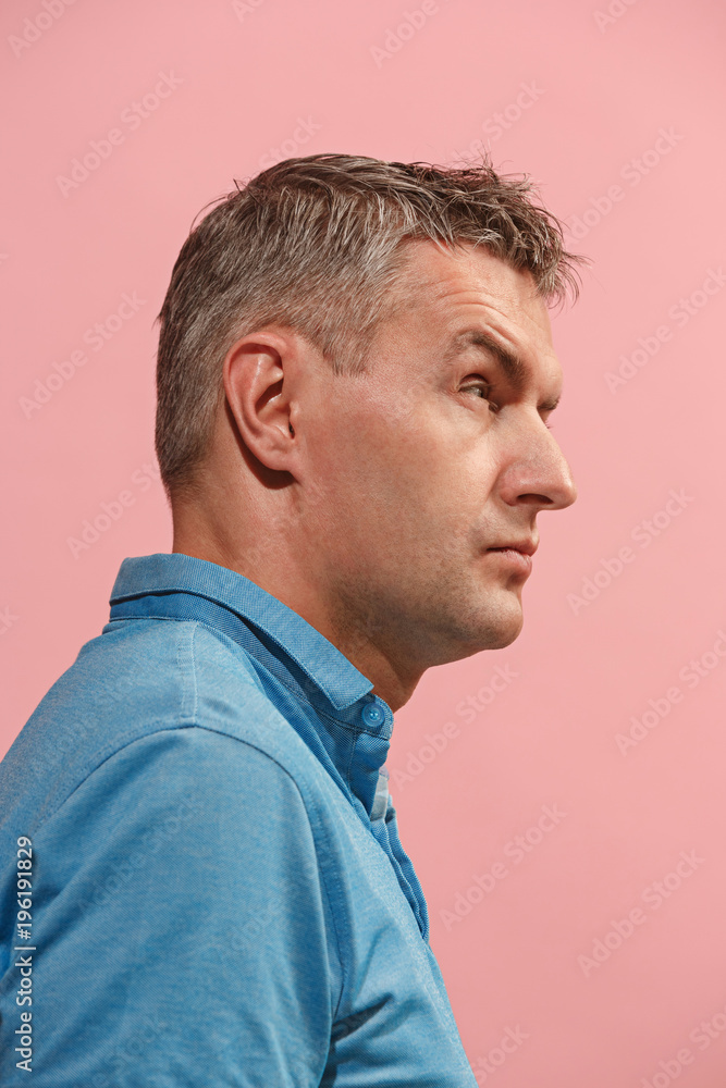 Fototapeta premium Suspiciont. Doubtful pensive man with thoughtful expression making choice against pink background