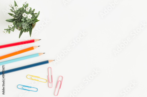 Flat lay photo of office desk with colorful pencil and paper clip,copy space top view