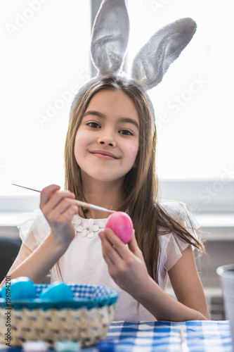 Little girl having fun while painting Easter egg. photo