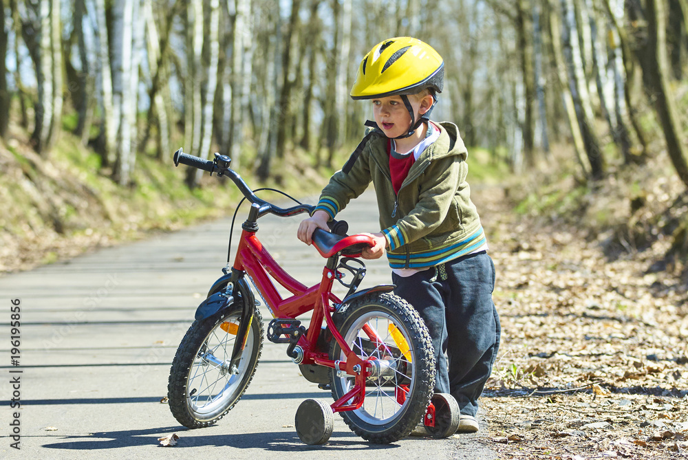 Little child boy cycling on bicycle in green park outdoor in spring. A child is riding a children's bike with support training wheels wearing safety helmet
Little child boy cycling on bicycle in green park outdoor in spring. A child is riding a children's bike with support training wheels wearing safety helmet