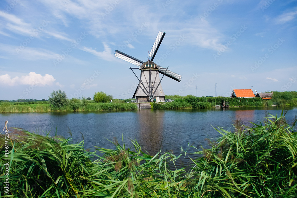 Classic windmills by the canal in Dutch village Kinderdijk in Holland. Landscape of famous tourist destination in Europe.