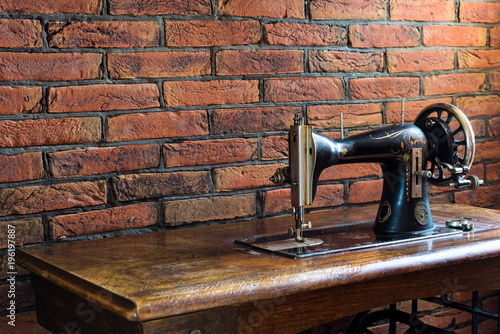 Old sewing machine with its wooden table near a wall of red bricks in Greece.