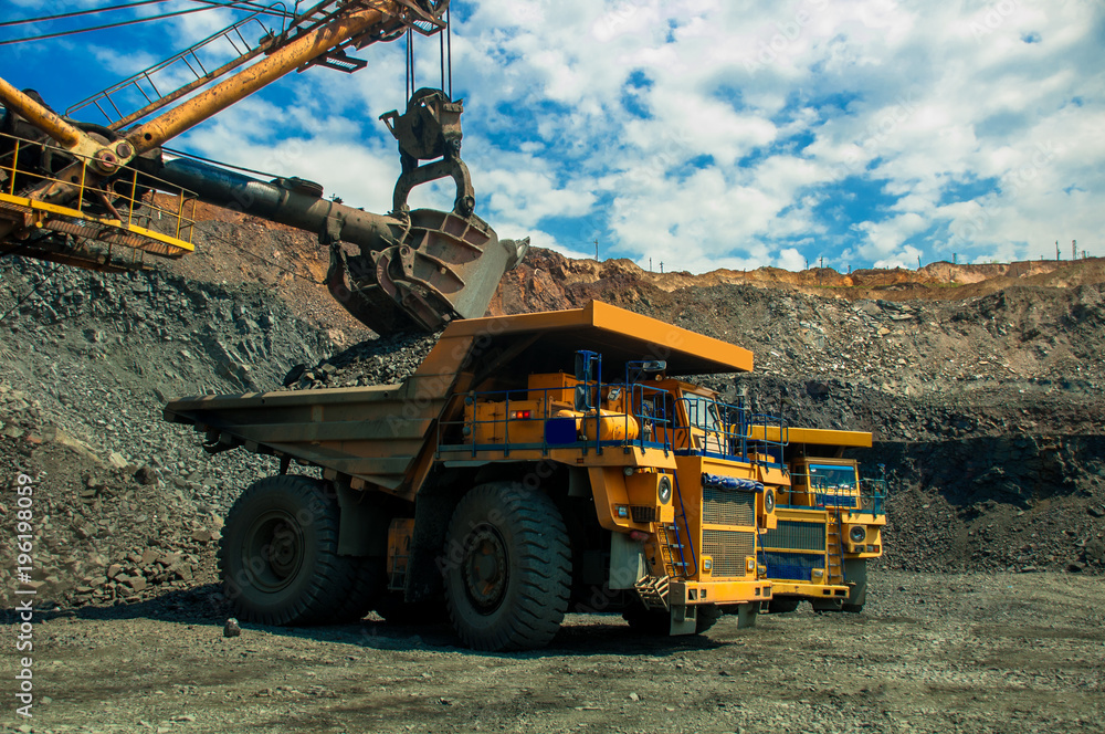 Excavator in the quarry loads the dumper with iron ore Excavator in the quarry loads the dumper with iron ore