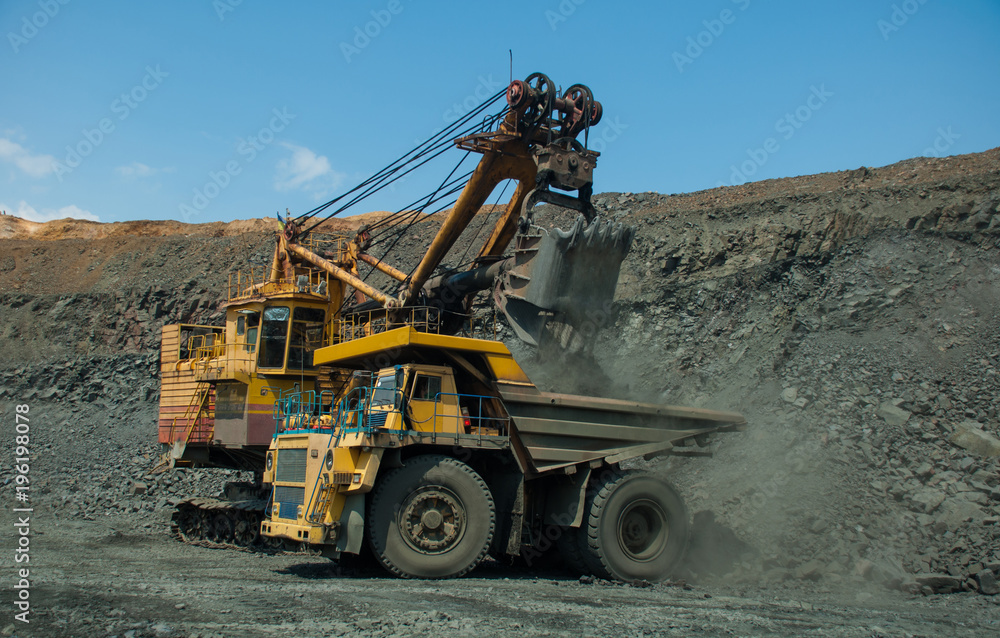 Excavator in the quarry loads the dumper with iron ore Excavator in the quarry loads the dumper with iron ore