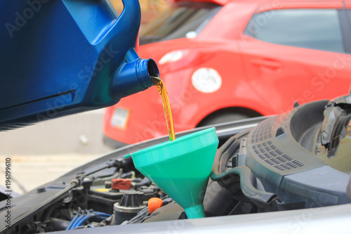 Close up of Mechanic pouring fresh oil to car engine at the repair garage
