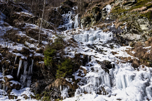 Mountain slopes covered in ice and icicles as the winter snow is melting during cold temperature, forming ice waterfalls along the slopes