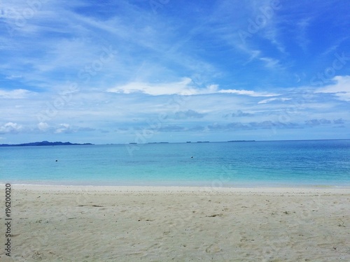 Ocean view of blue sky  beautiful clouds and pacific crystal turquoise water beside a tropical island with powdery white sand . Palambak island  Indonesia