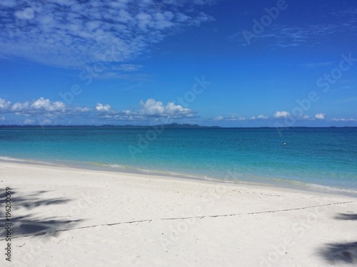 Ocean view of blue sky  beautiful clouds and pacific crystal turquoise water beside a tropical island with powdery white sand . Palambak island  Indonesia