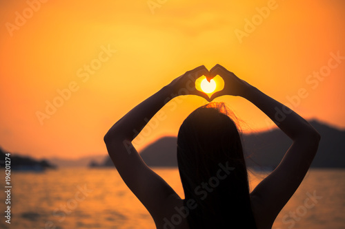 Woman with bikini making heart sign on beach