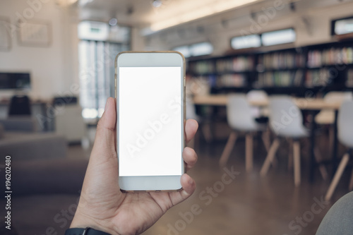 young asian man holding a phone at library