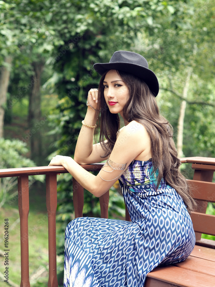 A Beautiful Lady in Blue Dress Sitting on A Bench at The Outdoor Balcony with Forest Background in Mae Hong Son Province, Thailand.