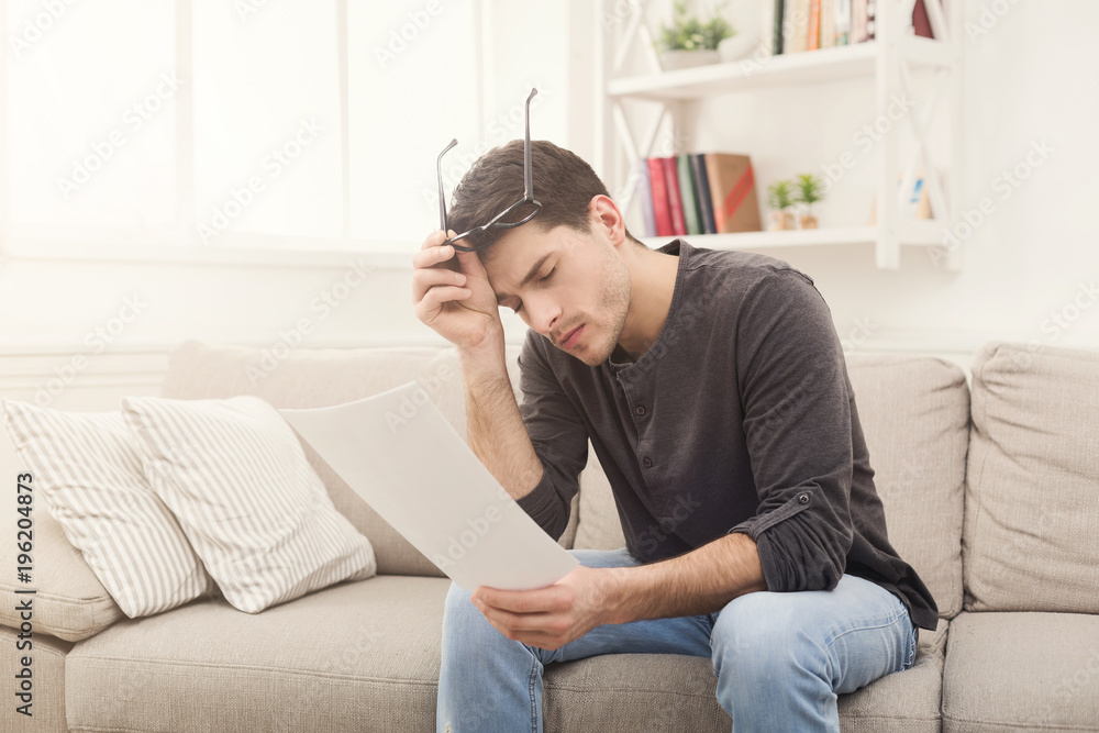Young tired businessman reading report at home Young tired businessman reading report at home