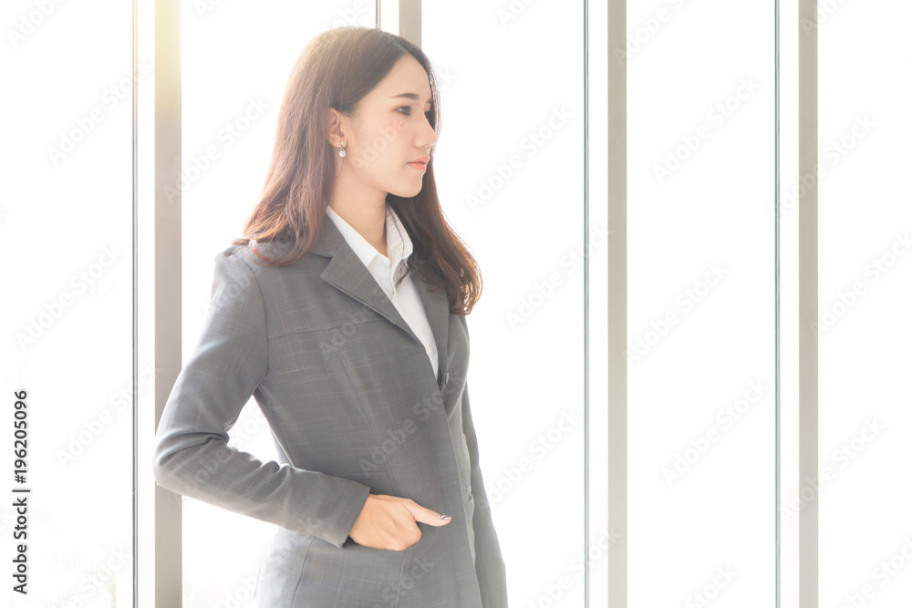 Portrait of a Confident attractive young Asian businesswoman wearing a suit with copy space standing on office window background. Portrait of a Confident attractive young Asian businesswoman wearing a suit with copy space standing on office window background.
