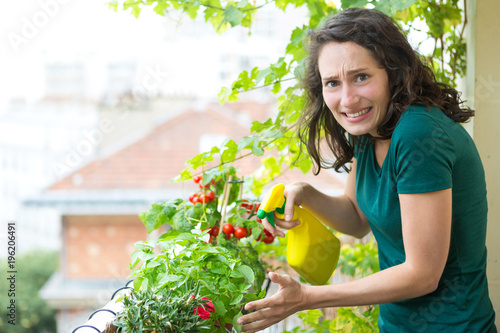 Young woman hoping not killing her plant with chemistral product - Ecology and nature theme photo