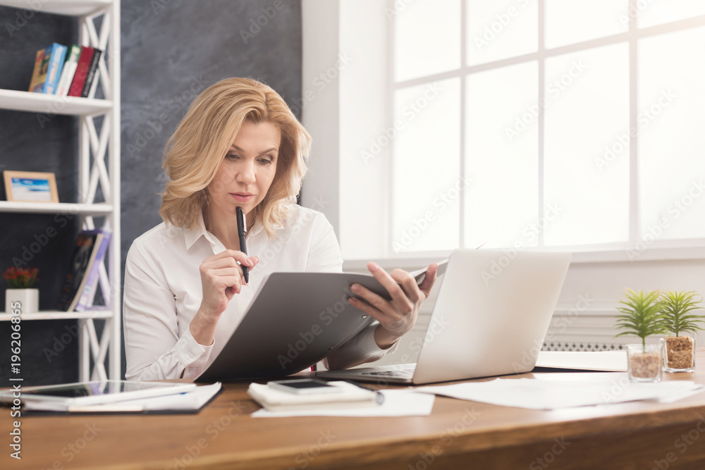 Thoughtful businesswoman reading document at office desktop Thoughtful businesswoman reading document at office desktop