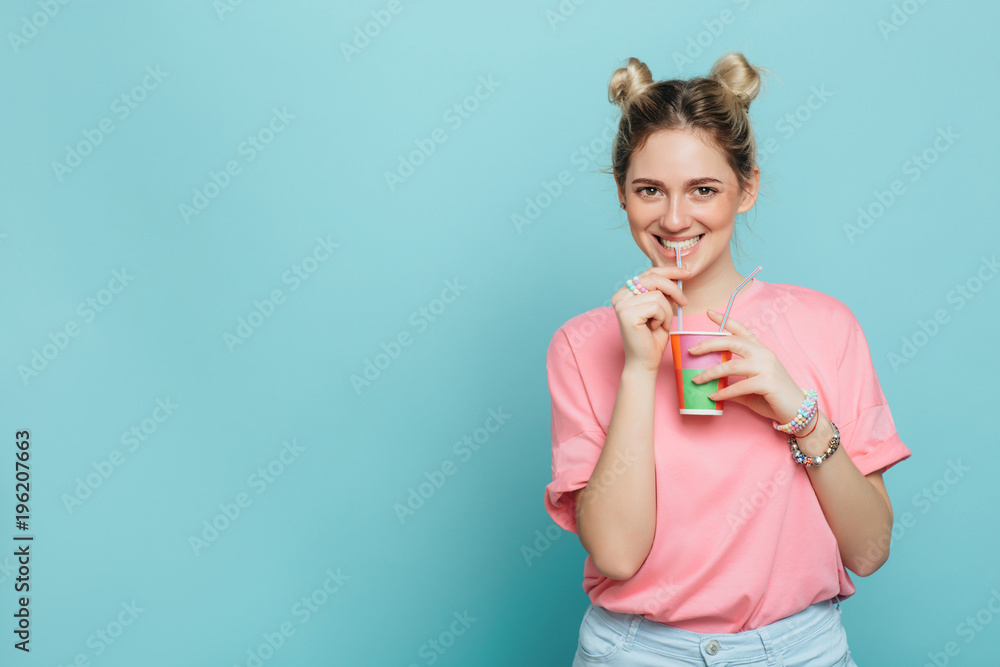 modern young woman holding paper cup and drinking beverage with drinking straw on a blue pastel background. Party time modern young woman holding paper cup and drinking beverage with drinking straw on a blue pastel background. Party time