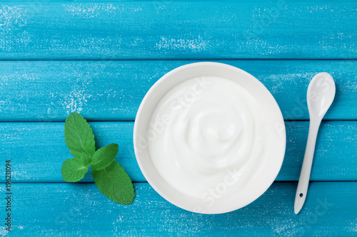 Fresh greek yogurt in bowl on blue vintage table top view.