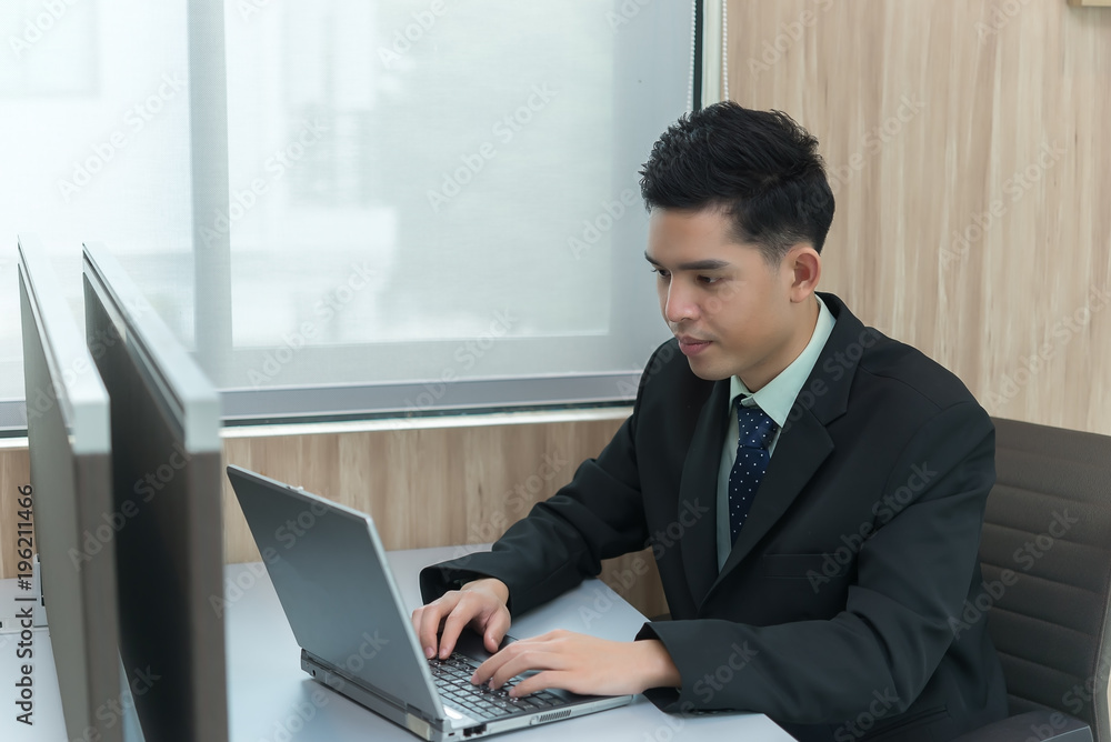 Young asian employee working at laptop during working day in office,Businessman happy with smile in the office,thailand people at company Young asian employee working at laptop during working day in office,Businessman happy with smile in the office,thailand people at company
