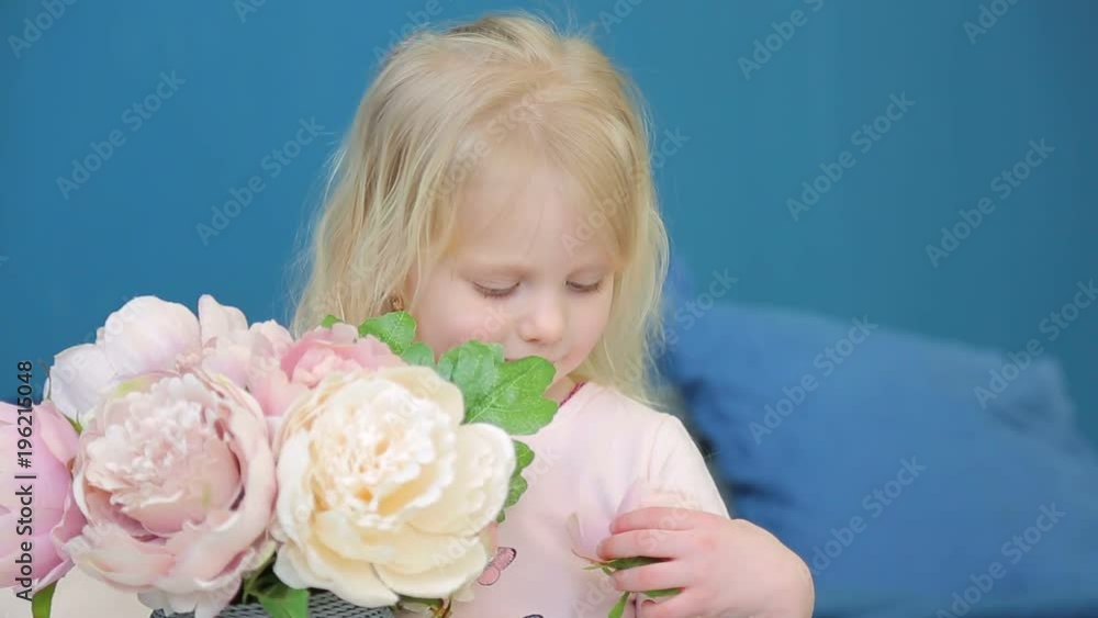 Little girl holding a large vase with flowers and plays them in his room on the bed Little girl holding a large vase with flowers and plays them in his room on the bed