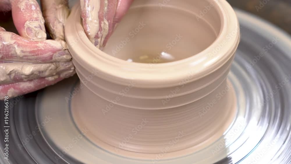 Closeup of a muddy hands creating a clayware on the spinning potter's wheel. Closeup of a muddy hands creating a clayware on the spinning potter's wheel.