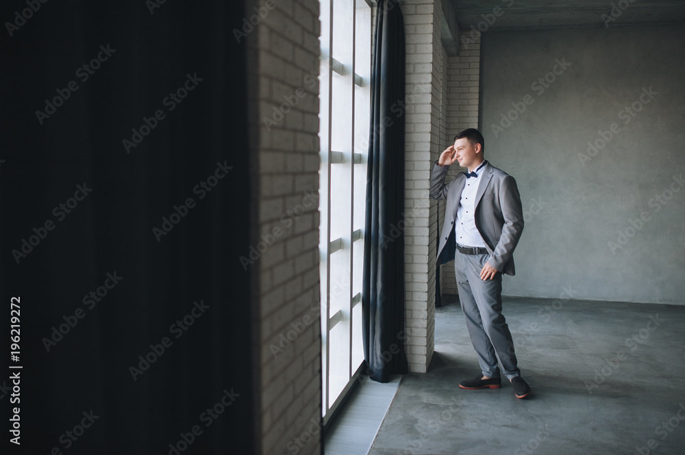 A beautiful and stylish bridegroom in an interesting studio stands near the window. A fashionable wedding with a beautiful bridegroom. A beautiful and stylish bridegroom in an interesting studio stands near the window. A fashionable wedding with a beautiful bridegroom.